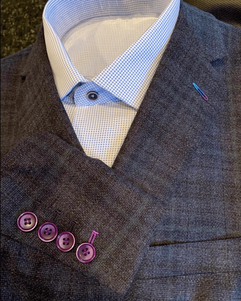 Custom charcoal jacket with purple sleeve buttons over a blue check dress shirt