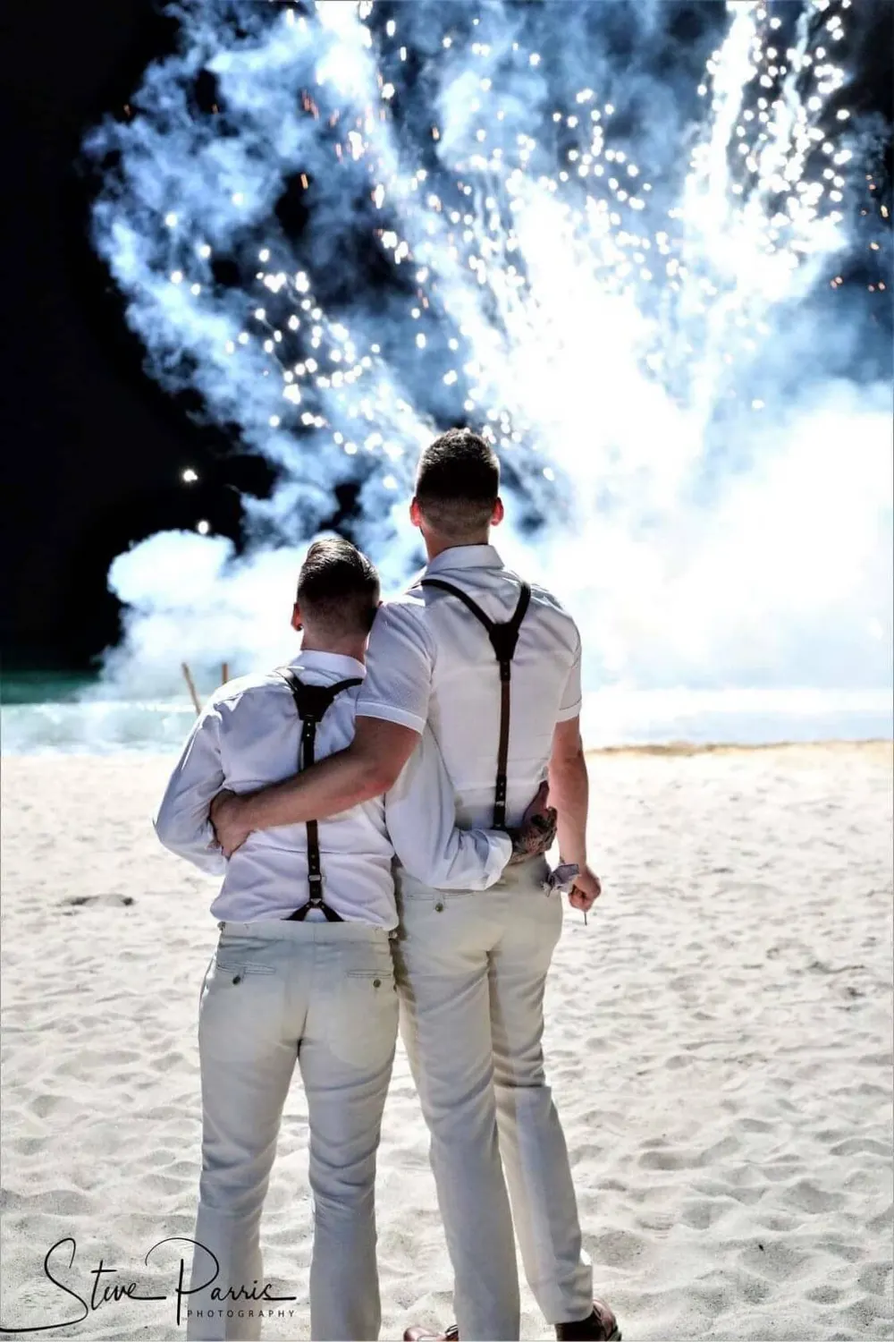 Two grooms in custom wedding attire on the beach
